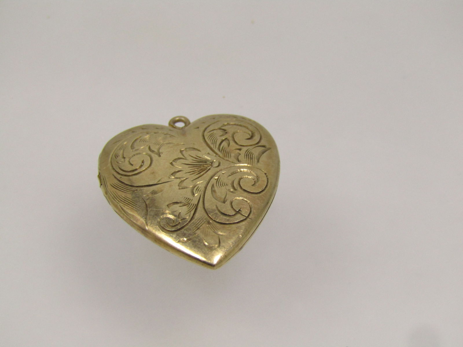 Vintage 10kt Scrolled Heart Locket, 3.42 gr. 1930's-1940's: Vintage 10kt Scrolled Heart Locket, 3.42 grams. 1930's-1940's. This is appx. 1" tall and 7/8" wide. It has a few dents on the back as can be seen in the photos. Holds two photos. It is not signed by t