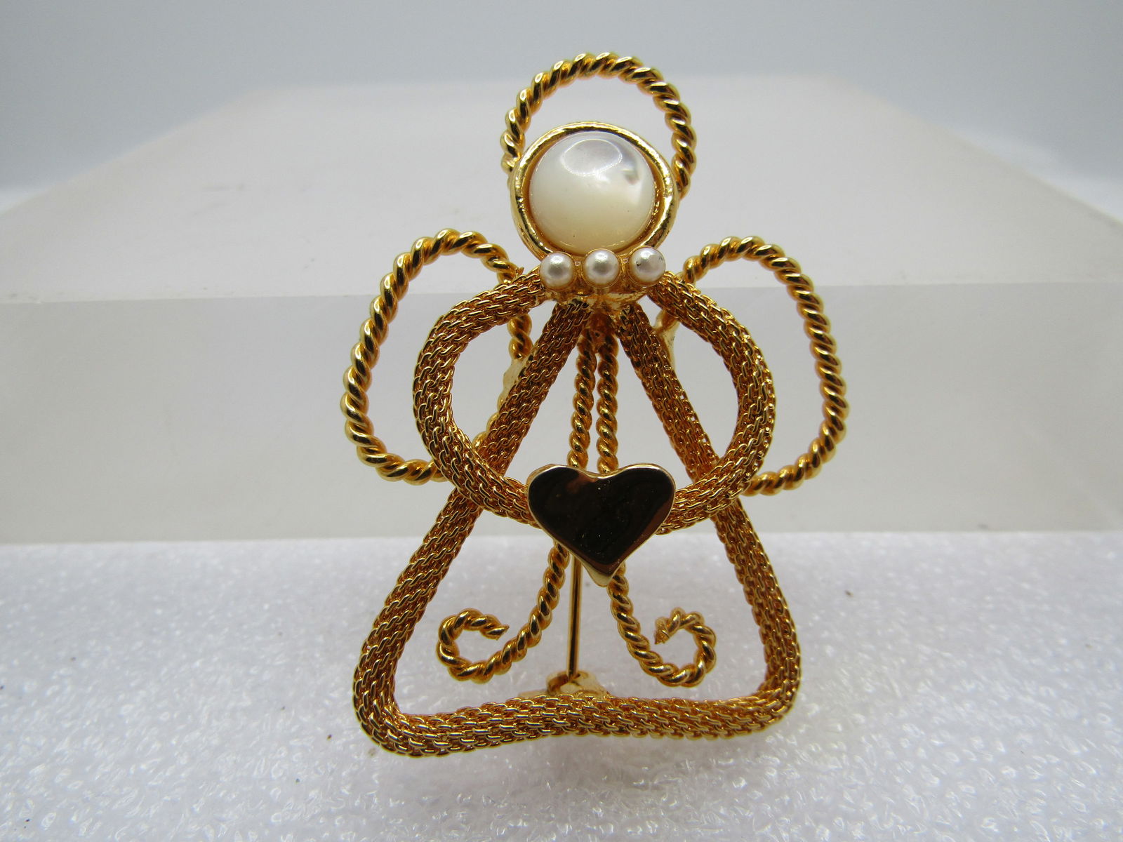 Vintage Angel & Heart Brooch, 1980's-1990's: Vintage Angel & Heart Brooch, 1980's-1990's. It is mdae with twisted and mesh gold tone metal. Faux moonstone 7.5mm head and a smooth and shiny heart. It is 1.75" tall and 1.5" wide. Very good and ver
