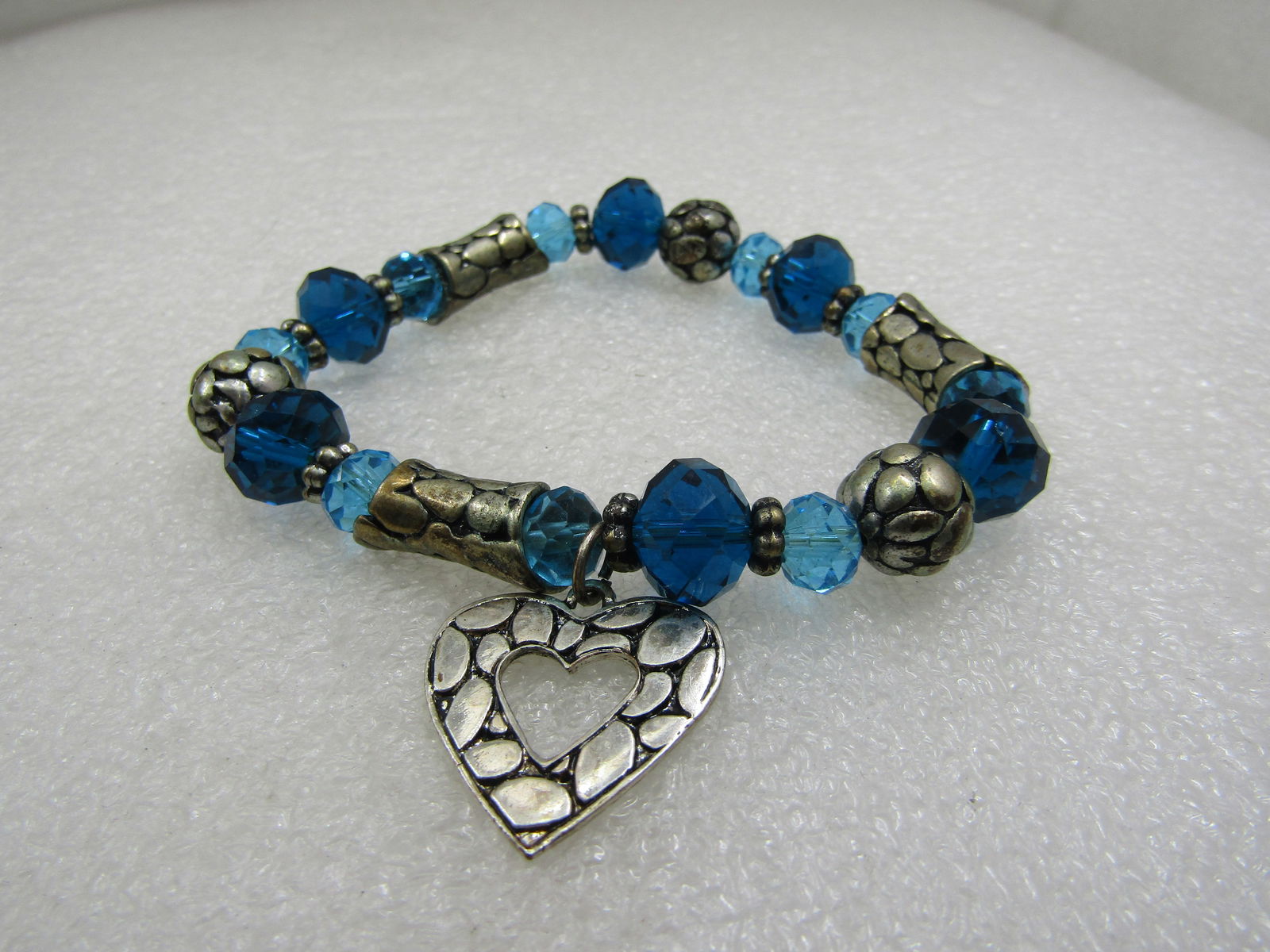 Aqua Crystal & Heart Stretch Bracelet, Fits Most. require restringing at some point as the water: Aqua Crystal & Heart Stretch Bracelet, Fits Most. Silver tone long and round beads with a textured nugget like design and also on the 1" heart charm that dangles from the bracelet. The beads are a lig
