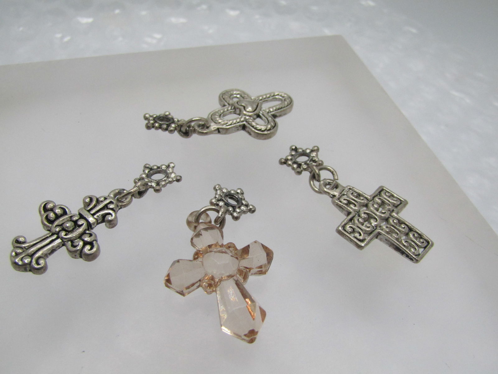 Four Cross Slides/Pendants, Silver Tone & Lucite, Mixed Designs: Four Cross Slides/Pendants, Silver Tone & Lucite, Mixed Designs. They are appx. 1.25" to 1.5", The peach lucite faceted cross has a silver tone ring and is appx. 1.25. The other three are silver tone,