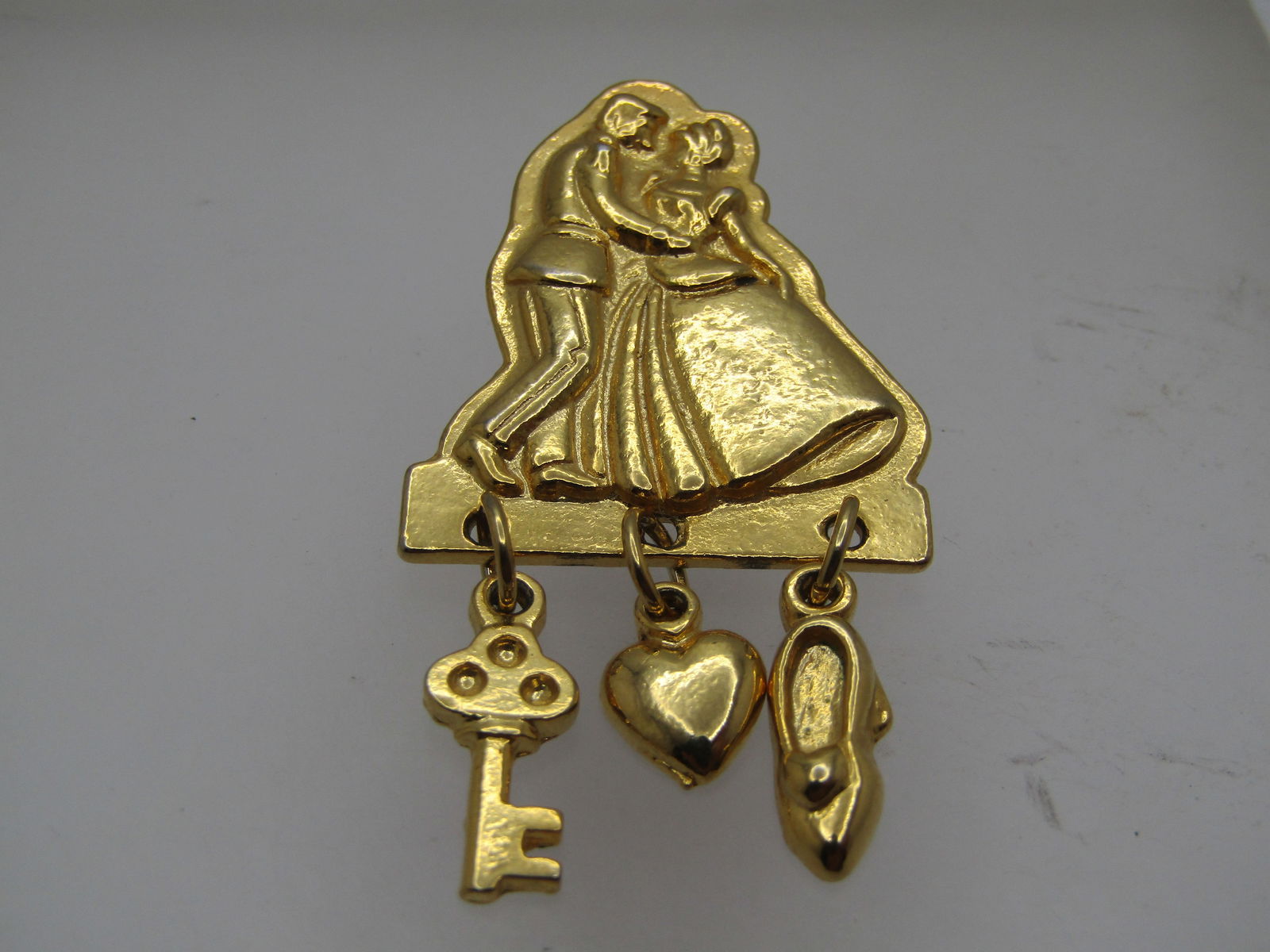 Vintage Disney Cinderella & Prince Charming Brooch, Dancing, 1990's: Vintage Disney Cinderella & Prince Charming Brooch, Dancing, 1990's . Gold tone and appx. 2" long and 1-1/8" wide. It features the dancing couple on top with a drop key, heart, and slipper. Signed Dis