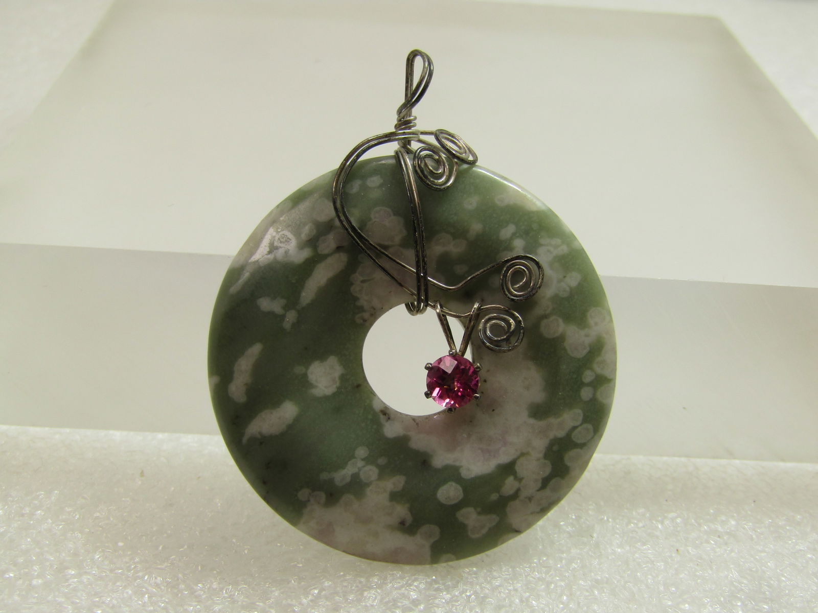 Vintage Peace Jade Sterling Wrapped Pendant , Pink Topaz Center Stone, 1980's-1990's: Vintage Peace Jade Sterling Wrapped Pendant , Pink Topaz Center Stone, 1-5/8", 1980's-1990's. This is wrapped with a double strand of silver wire that tests as sterling with a hand made design of coil