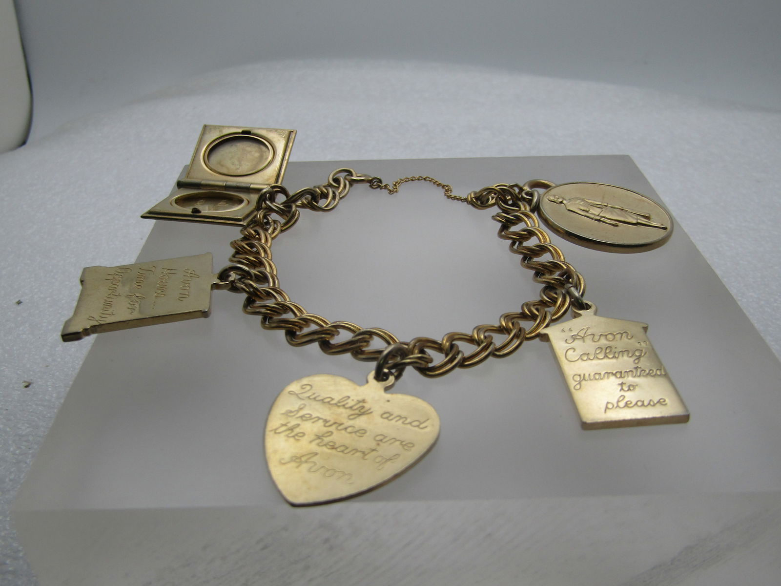 Vintage 10kt G.F. 1960's Avon Charm Bracelet, 7.25" President's Club & More: Vintage 10kt G.F. 1960's Avon Charm Bracelet, 7.25" President's Club & More, Safety Chain, spring clasp. This has a rose book locket with Avon a history of Beauty since 19886 on the back and is hinged