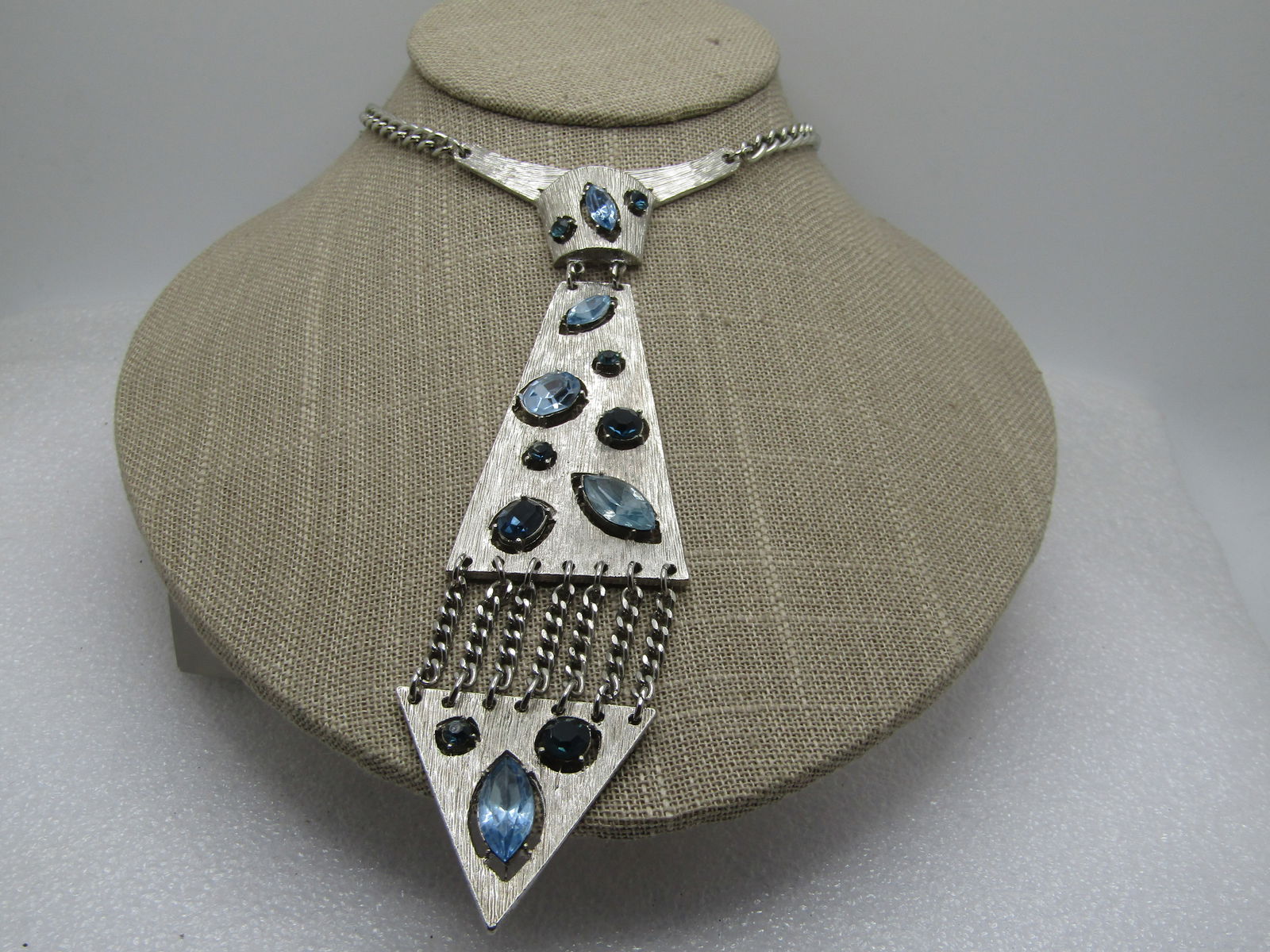 Vintage Blue Rhinestone Tie Necklace, 1960's-1970's, 15.5": Vintage Blue Rhinestone Tie Necklace, 1960's-1970's, 15.5". Hook clasp, silver tone chain that is appx. 4.5mm wide. The tie is textured with raised light blue marquise stones, oval and darker round an