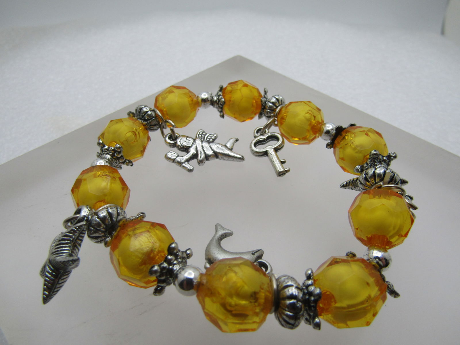 Stretch Charm Bracelet, Yellow faceted, Up to 7.5", 1990's: Stretch Charm Bracelet, Yellow faceted, Up to 7.5", 1990's . Yellow faceted acrylic beads with white center that are appx. 11.5mm wide. Between each bead are fluted and star shaped silver tone beads.