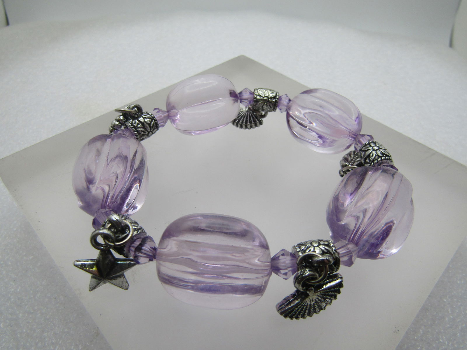 Stretch Charm Bracelet, Lavender Beads, 1990's: Stretch Charm Bracelet, Lavender Beads, 1990's. Five chunky clear lavender acrylic beads that are appx. 16mm by 22mm with a slide dangling charm link between with two fans, star, leaf, and heart. Will