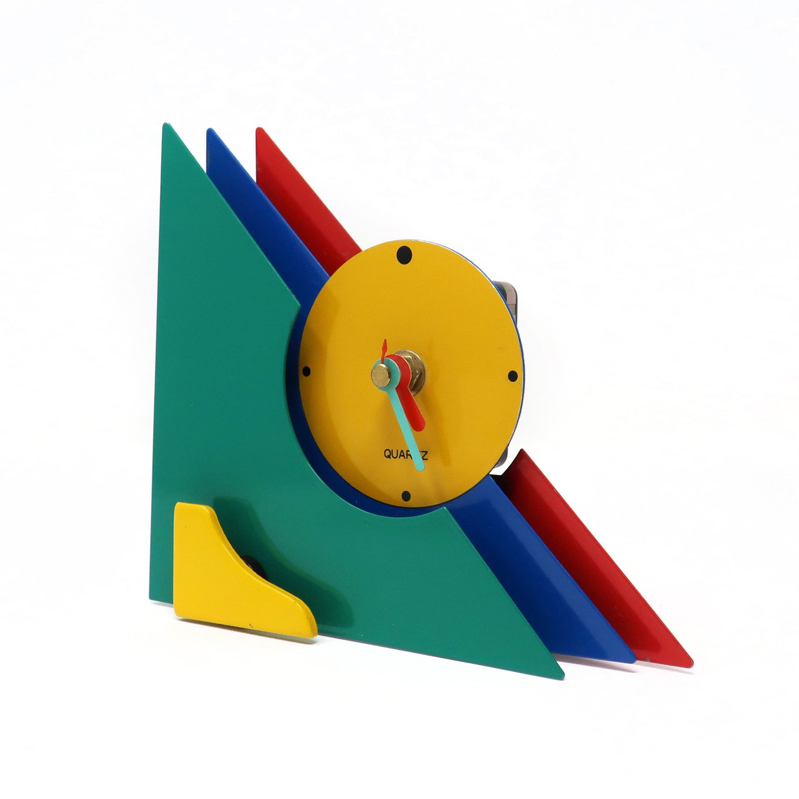 1980s Multicolor Stacked Desk or Mantel Clock: With a stunning combination of red, blue, green, and yellow enameled metal, and yellow lucite accents, this postmodern clock is designed with a stacked triangular design that gives it a rare and beaut
