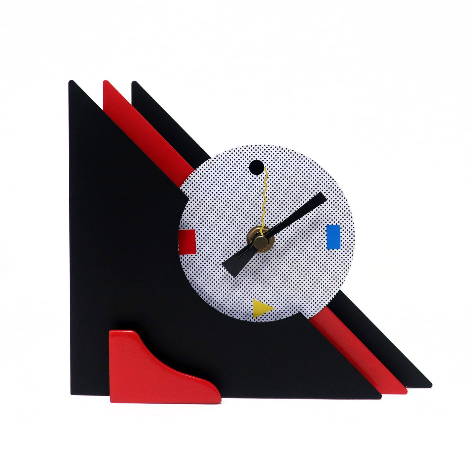 1980s Red & Black Stacked Desk or Mantel Clock: With a stunning combination of red and black enameled metal, red lucite accents, and primary colored shapes at 3, 6, and 9, this postmodern clock is designed with a stacked triangular design that give