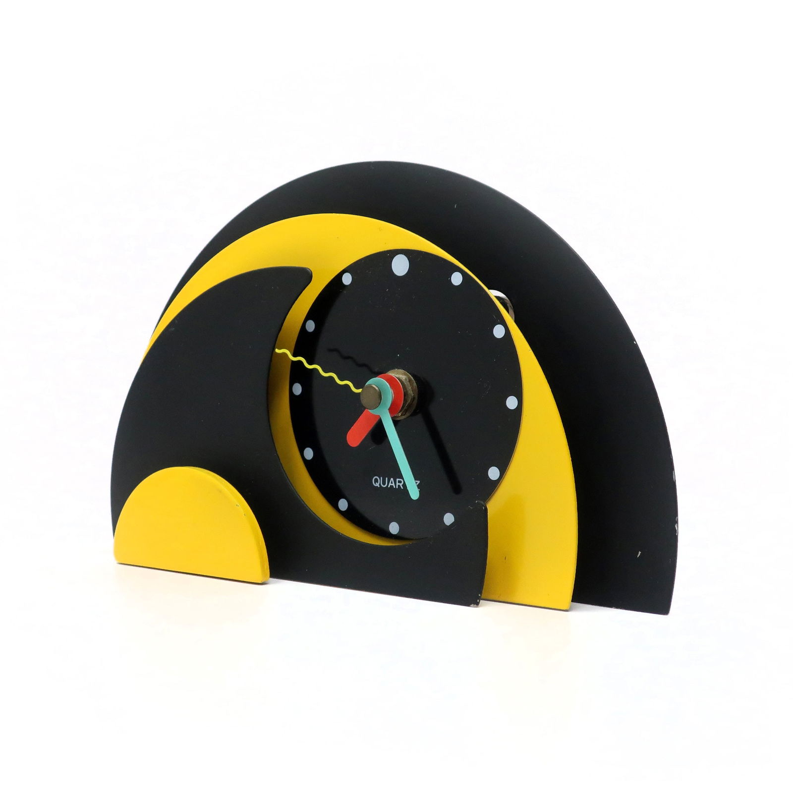 1980s Yellow & Black Stacked Desk or Mantel Clock: With a stunning combination of yellow, black, and enameled metal, black lucite accents, and primary colored hands, this postmodern clock is designed with a stacked semi-circle design that gives it a r