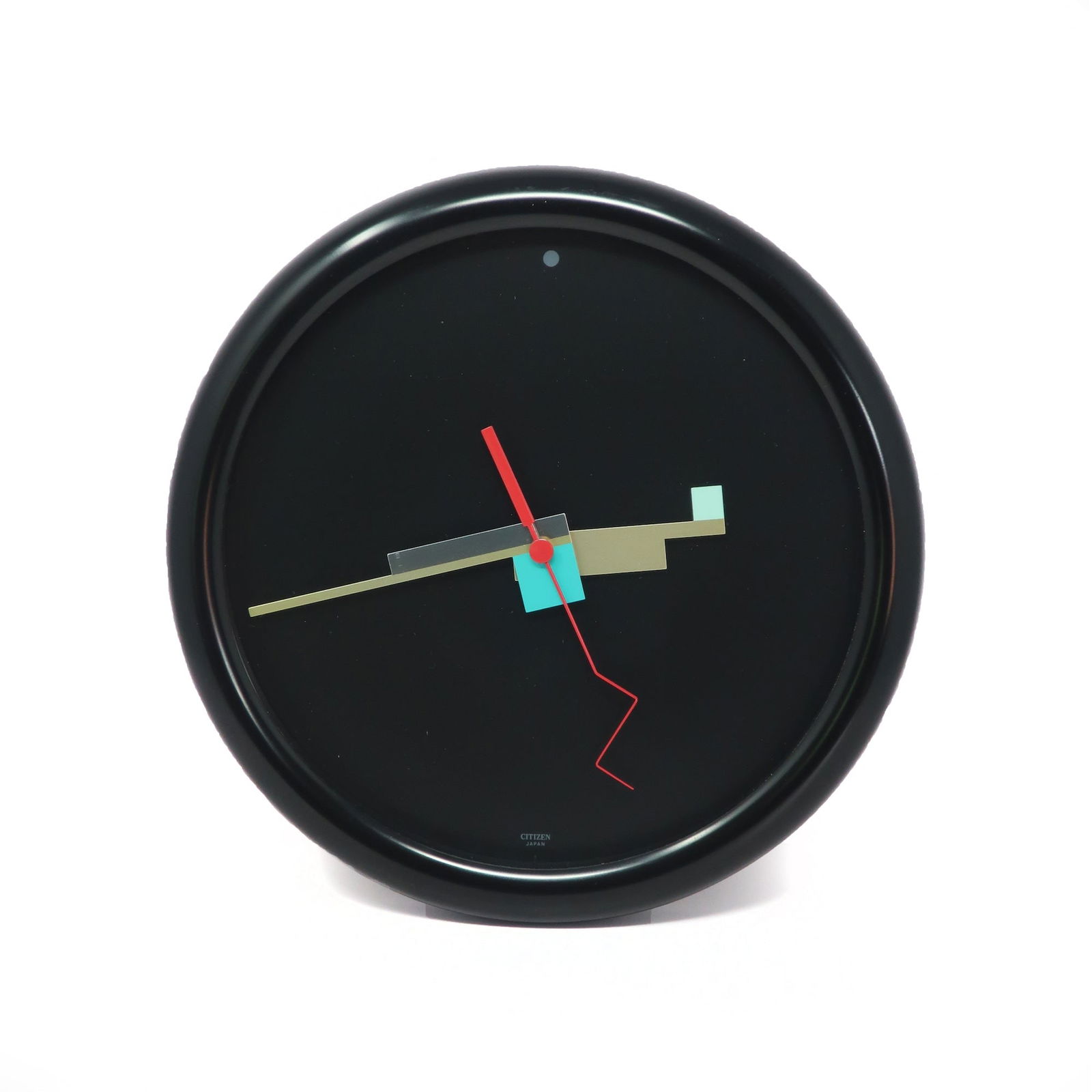 1980s Black Postmodern Wall Clock by Citizen: A truly stunning and rare Memphis Milano inspired wall clock made in Japan by Citizen. Black case, black face with a dot at 12 o'clock and "CITIZEN" at 6 o'clock, and amazing multi-colored geometric h