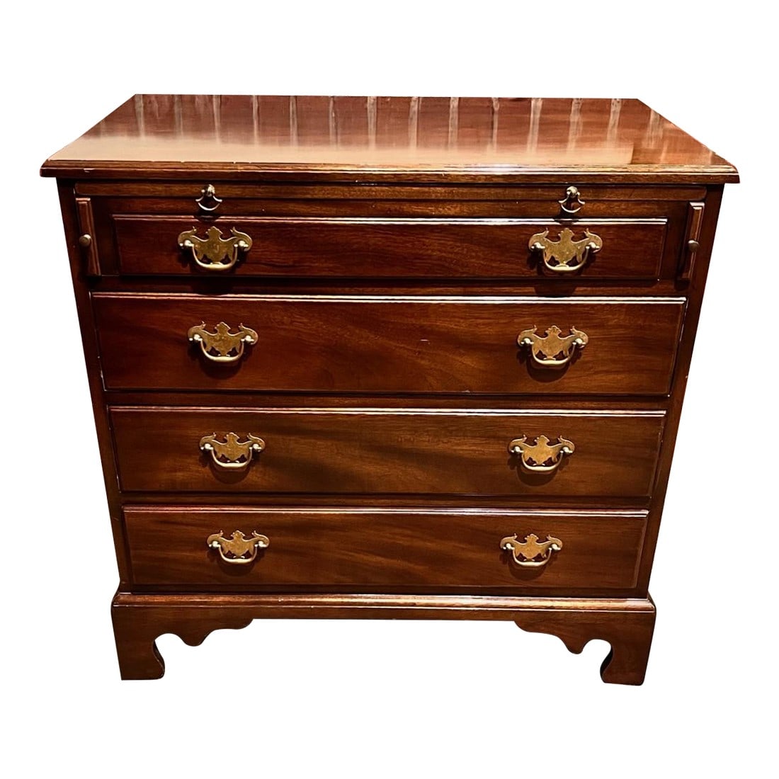 1970s Kittinger Furniture Company Chippendale Chest of Drawers: A Chippendale style chest of drawers that can also be used as a nightstand. It has a pull-out tray on top of the first drawers. The sides have pulls for easy transportation. A cherry finish still has