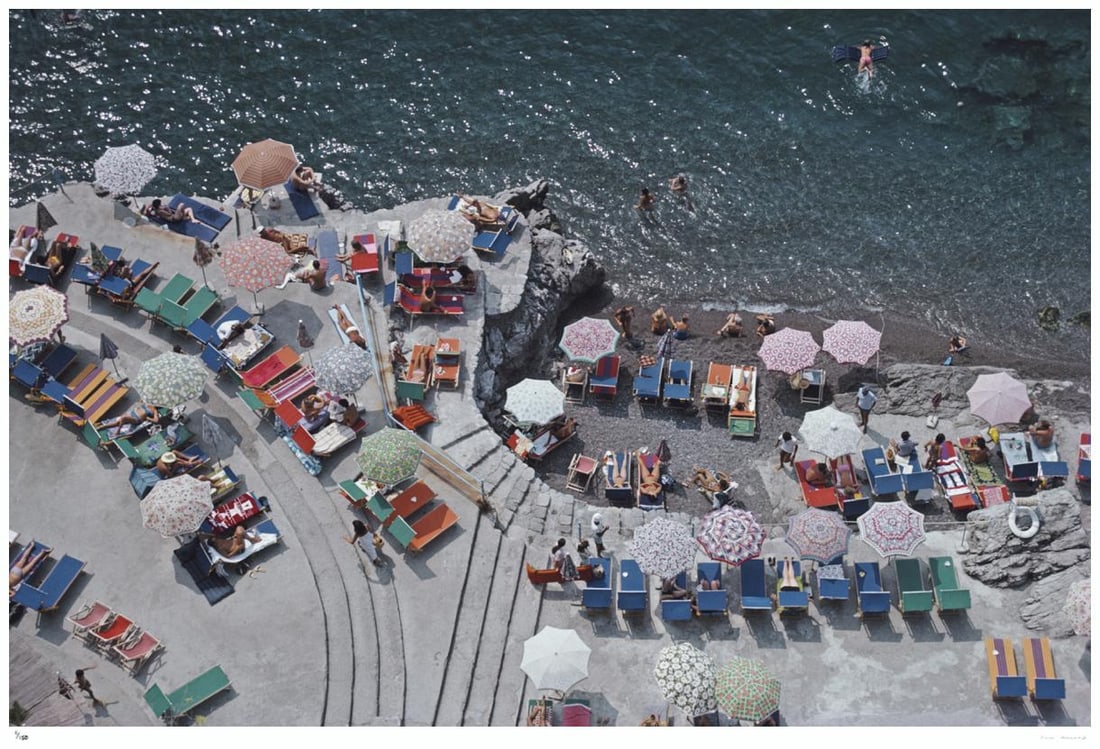Positano Beach 1979 - Slim Aarons Estate Stamped: 1979 (printed later): Title: Positano Beach 1979 - Slim Aarons Estate Stamped: 1979 (printed later) Description: Positano Beach 1979 - Slim Aarons Estate Stamped Elevated view looking down on sunbathers and parasols on