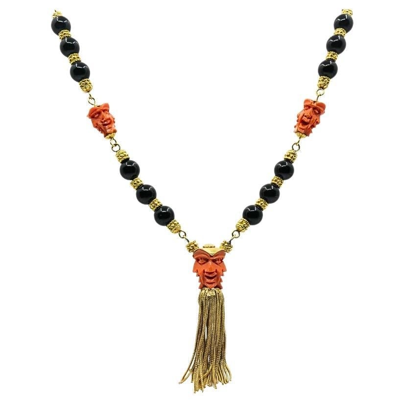 Vintage 18k Gold Carved Coral Devil Mask Onyx Tassel Necklace: Title: Vintage 18k Gold Carved Coral Devil Mask Onyx Tassel Necklace Description: This vintage 18k yellow gold necklace features carved coral devil mask stations and polished black onyx beads arranged