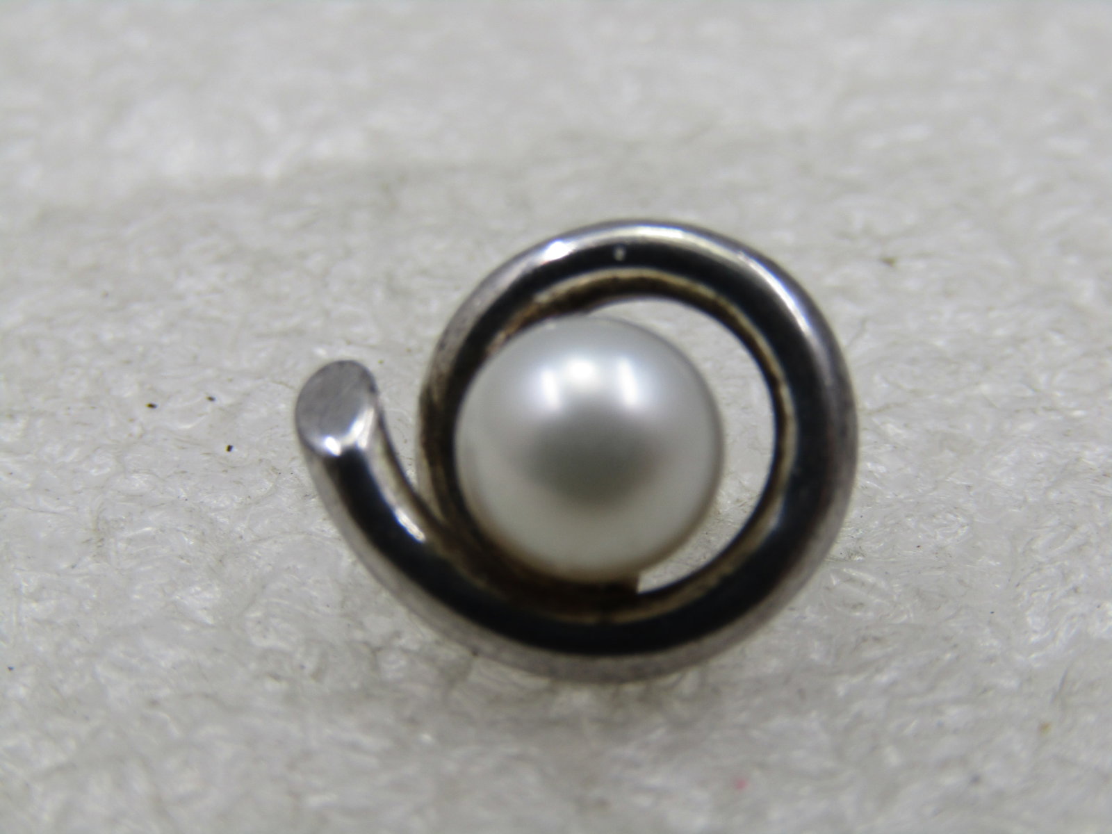 Vintage Sterling Pearl Single Earring, Pierced, 6.5mm: Vintage Sterling Pearl Single Earring, Pierced, 6.5mm. Very nice quality ring with a round overlapping circle frame around the appx. 6.5mm white pearl, cultured. Weight of the earrings ia ppx. 2.60 gr