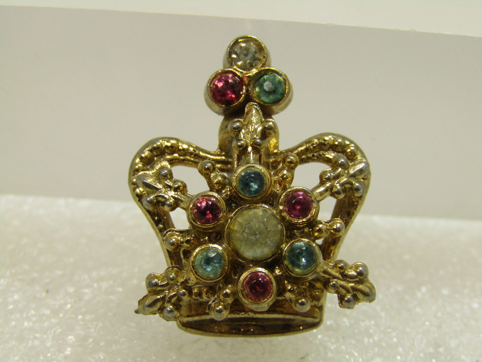 Vintage Rhinestone Crown Brooch, 1950's-1960's: Vintage Rhinestone Crown Brooch, 1950's-1960's. This is appx. 1-1/8" tall and 7/8" wide. It has pink, blue, and clear rhienstones set higher than the crown with fleru-de-lis accents. Gold tone. It is