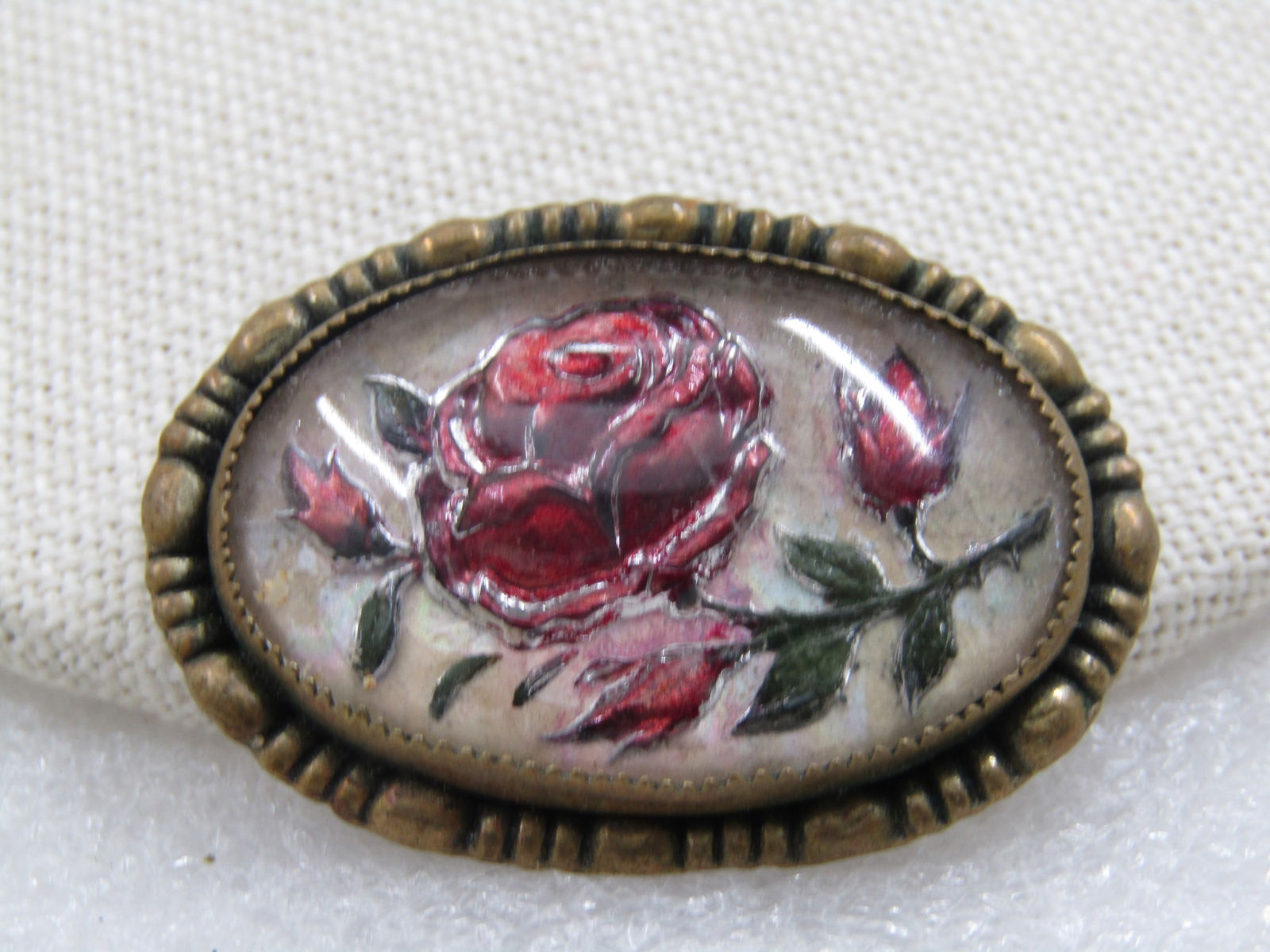 Vintage Reverse Carved Painted Rose Brooch, C-Clasp, 1930's: Vintage Reverse Carved Painted Rose Brooch, C-Clasp, 1930's. Brassy gold tone frame with large rose blossom and three buds and green leaves. Oval shaped, sawtooth bezel-set. 1.5" wide and 1-1/8"