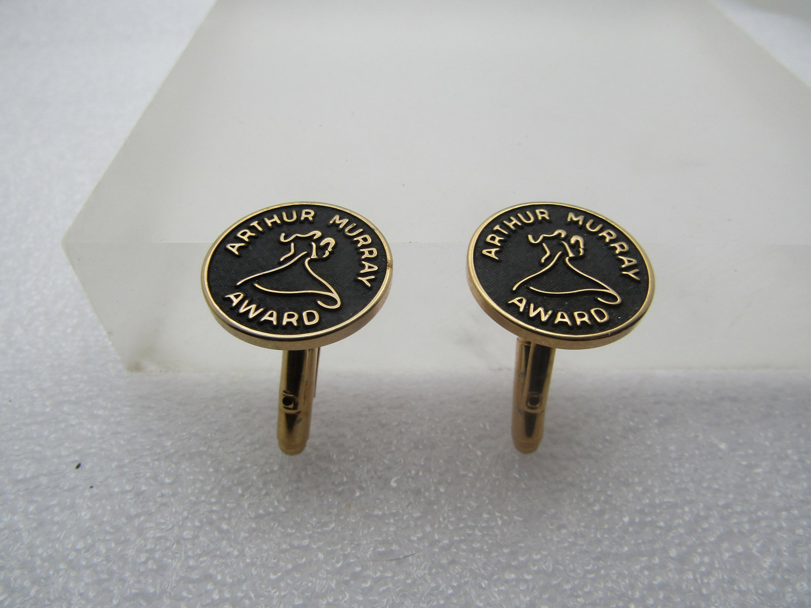 Arthur Murray Award Cuff Links, 1960's-1970's: Arthur Murray Award Cuff Links, 1960's-1970's. They are round, gold tone with recessed black textured background and raised arthur murray award and dancers . 7/8" round. It is not signed by the