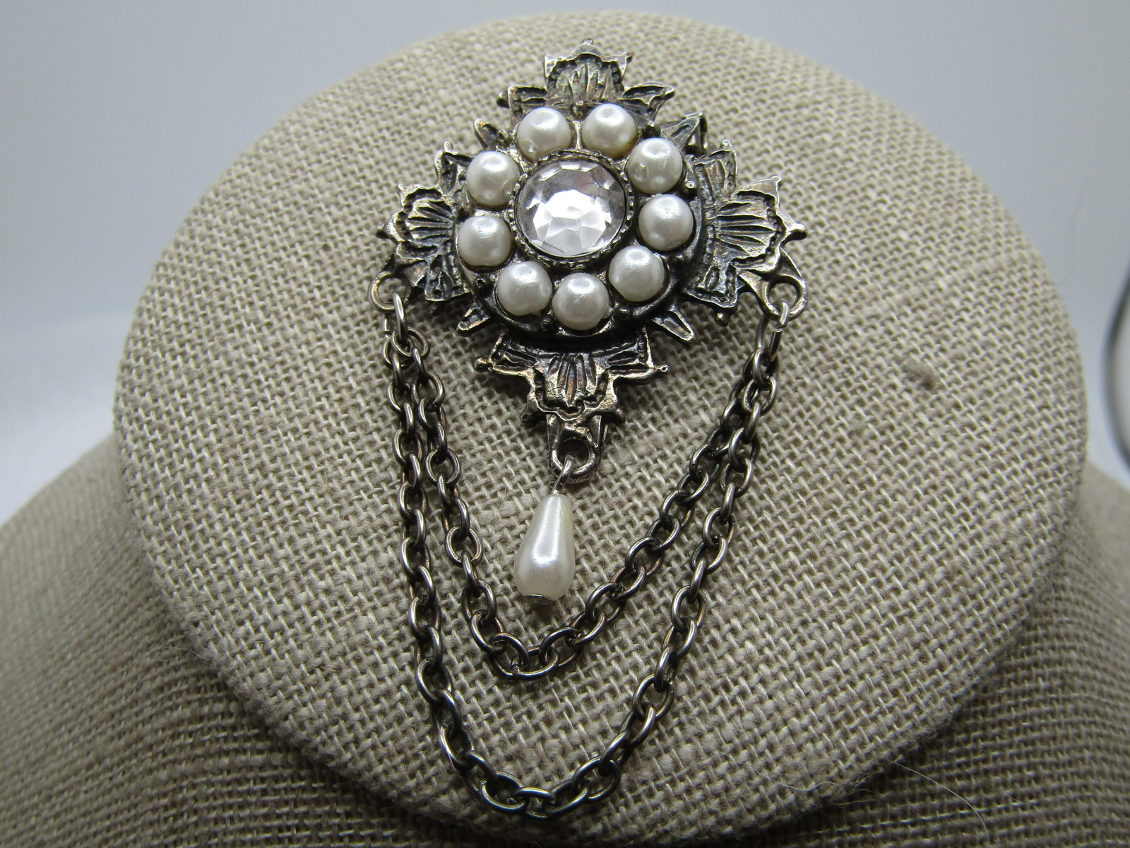 Vintage Faux Pearl Rhinestone Swag Brooch, 1960's-1970's, signed: Vintage Faux Pearl Rhinestone Swag Brooch, 1960's-1970's. It is appx. 2.25" long and 1.25" wide. Silver tone. It has two draping chains under the brooch with a teardrop faux pearl dange. The