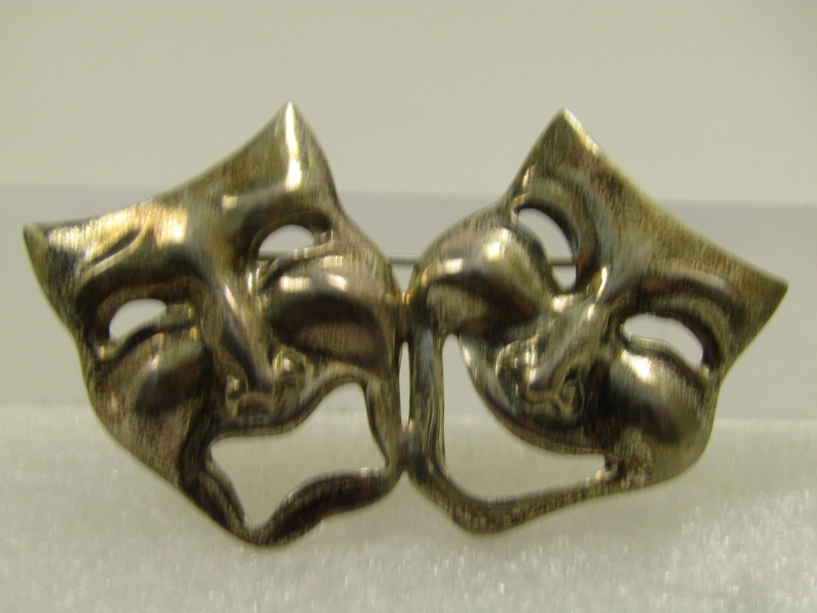 Vintage Sterling Comedy Tragedy Mask Brooch, 1960's-1970's: Vintage Sterling Comedy Tragedy Mask Brooch, 1960's-1970's. The masks are joined at the cheeks and slanted outward. The brooch is appx. 2-5/8" wide and 1.5" tall. This is not marked or signed. It does