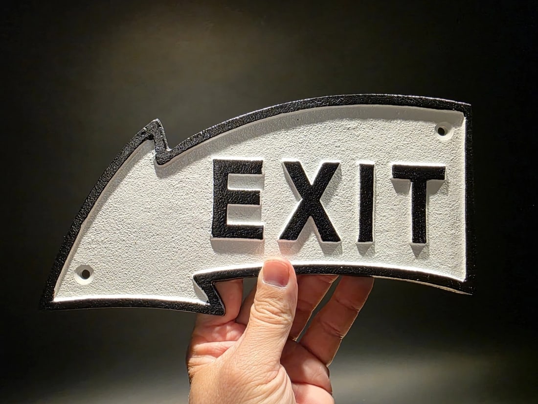 9 1/2" Cast Iron Arrow Exit Plaque Sign: 9 1/2" Long This solid cast iron EXIT arrow sign is inspired by early industrial and commercial wayfinding signage, where bold lettering and directional clarity were essential. The compact, arched arr