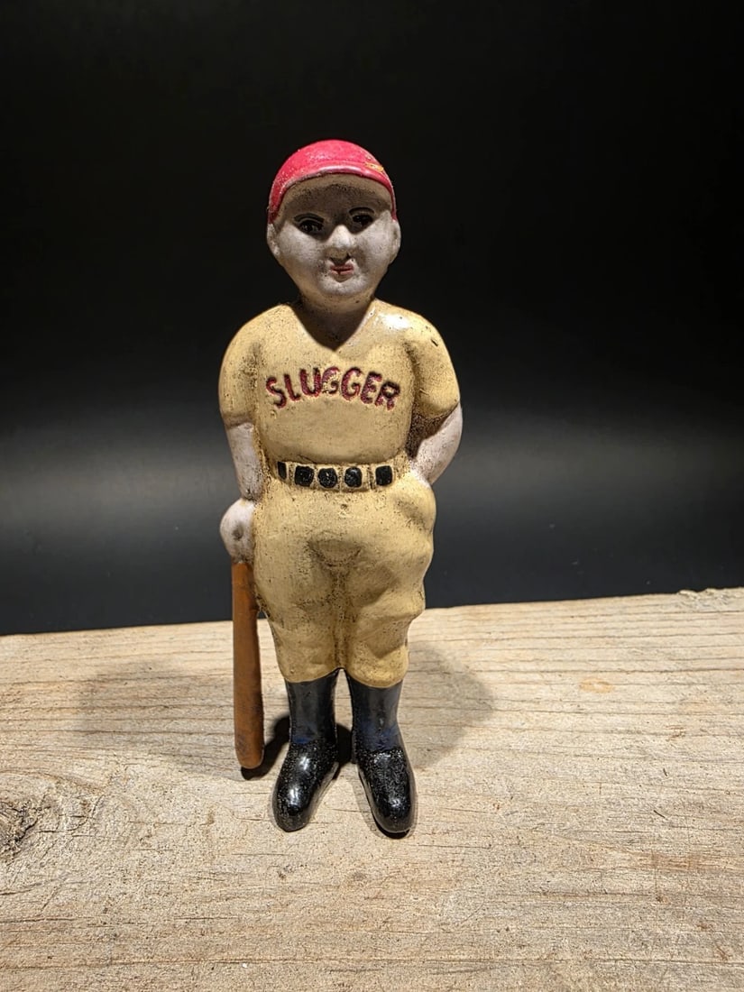 Cast Iron Slugger Coin Bank: 6 1/2" Tall This reproduction coin bank depicts a classic early baseball player, modeled after the beloved cast iron banks of the late 19th and early 20th centuries. The figure stands confidently with