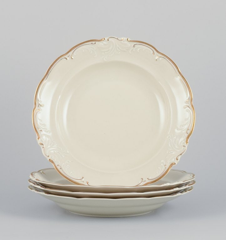 KPM, Poland. A set of four large deep porcelain plates in cream color. Gold-rim decoration. (1 of 5)