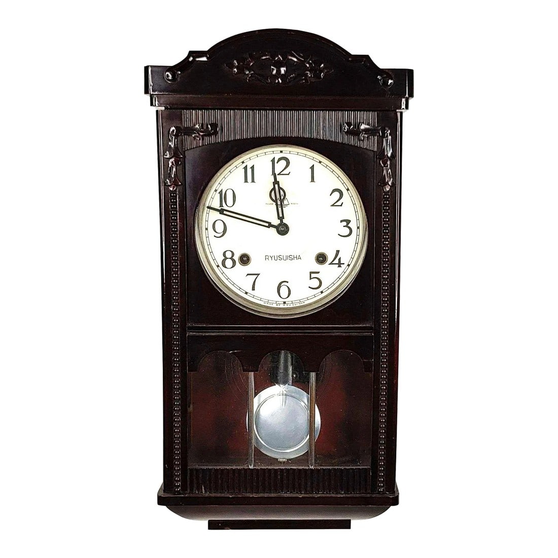 1960s Vintage Ryusuisha Wall Clock: A vintage Ryusuisha wall clock featuring a dark polish wood mahogany - colored clock case. The clock features a scalloped crest with carved floral accents above a round face with black numerals marked