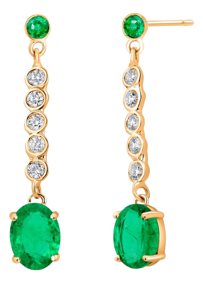 14 Karat Yellow Gold Drop Earrings With Emeralds and Diamonds - 2 Pieces: Elevate your elegance with these exquisite 14 Karat Yellow Gold Drop Earrings, showcasing a stunning combination of emeralds and diamonds. Each earring centers on a perfectly matched pair of oval