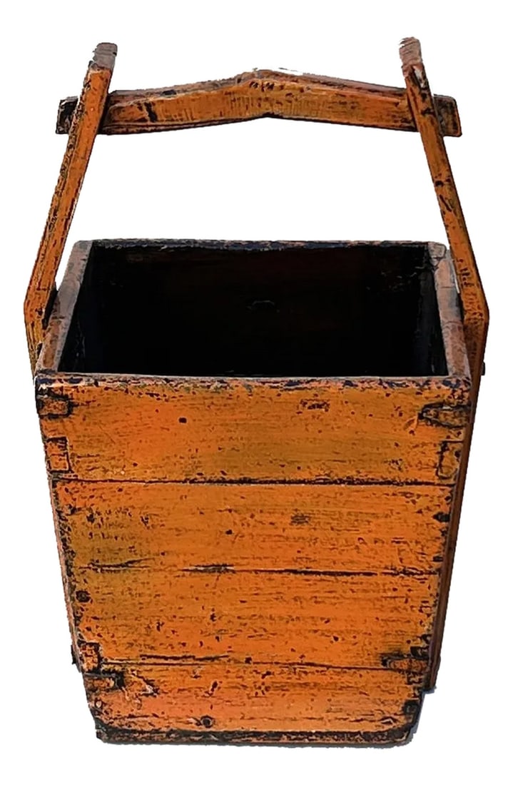 Vintage Rustic Orange Square With Handle Wood Bucket: This rustic wooden bucket exudes a timeless, weathered charm, showcasing the beauty of aged craftsmanship. Constructed from sturdy planks of wood, the bucket features a warm, faded orange hue that hin