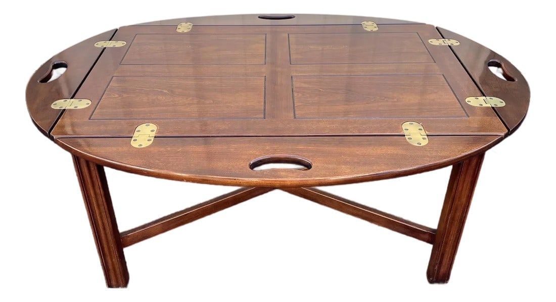 Drexel Furniture Cherry Butlers Tray Table: A mid-20th century butlers tray table made by renowned American furniture manufacturer, Drexel. This tray table is in a classic design, featuring handles on four articulating sides of the oval tableto