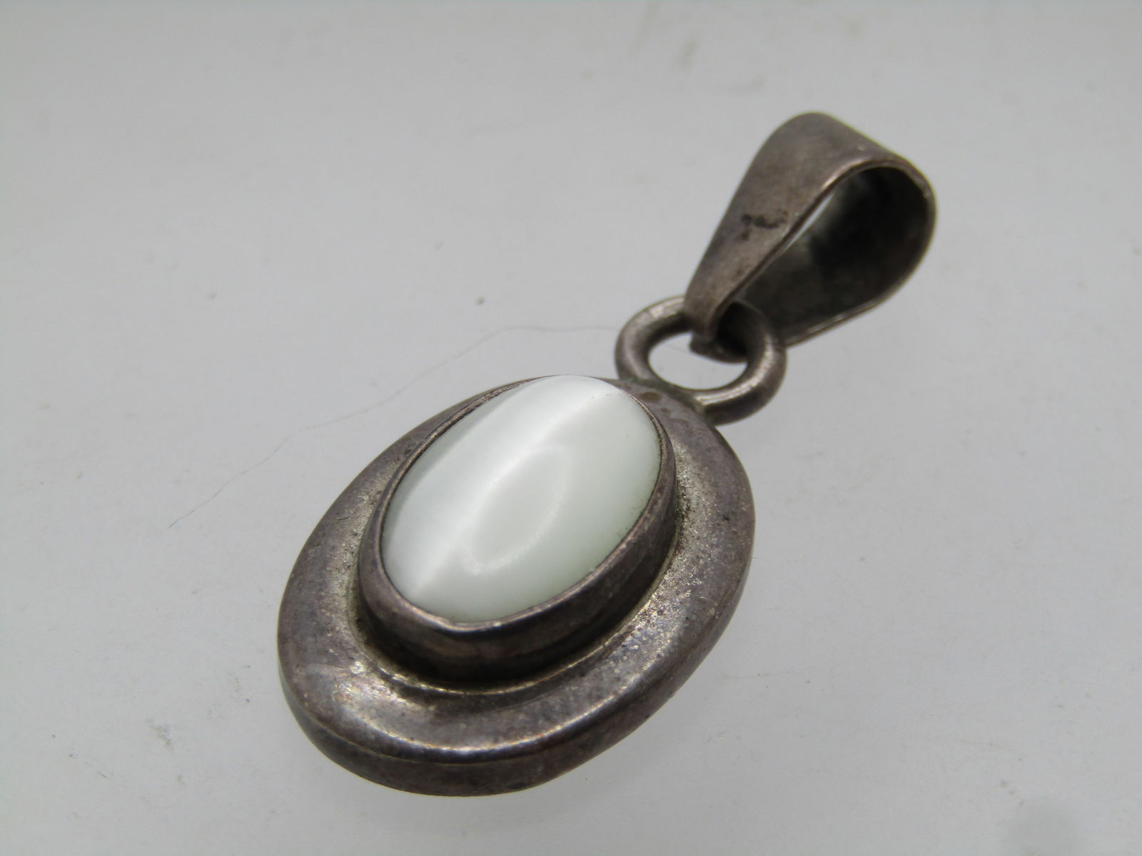 Vintage Sterling White Catseye Slide, Mexico , 1970's-1980's: Vintage Sterling White Catseye Slide, Mexico , 1970's-1980's. Oval 14mm by 10mm white catseye that is bezel set higher on the oval base. The slide is appx. 1.5" tall and 5/8" wide with a wide swing
