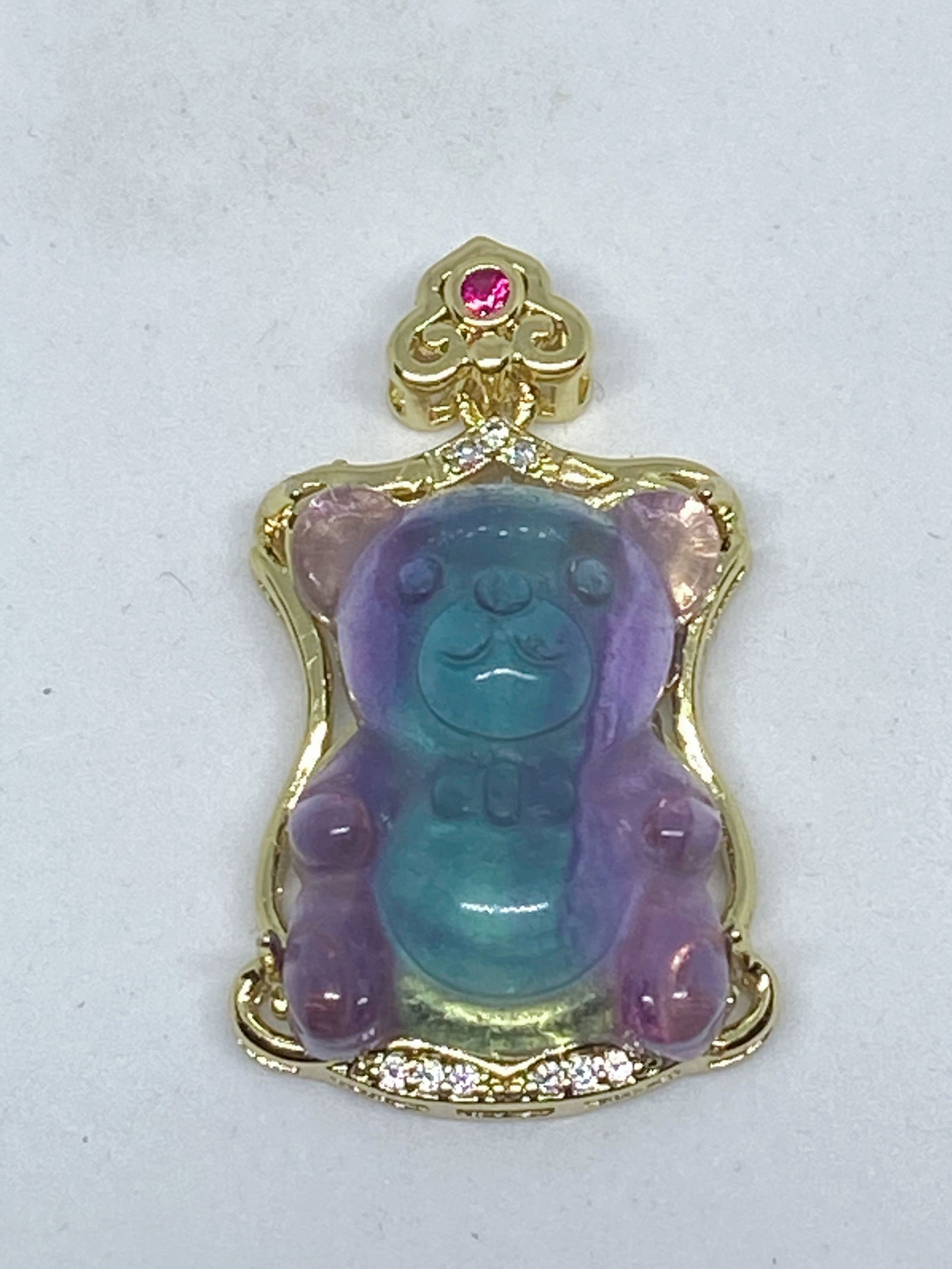 Natural Fluorite carved Teddy Bear Pendant: Title:Natural Fluorite carved Teddy Bear PendantDescription:Natural Fluorite carved Teddy Bear Pendant DESCRIPTION Stone type: Natural Fluorite Material: Gold plated Metal inlaid with Synthetic ruby