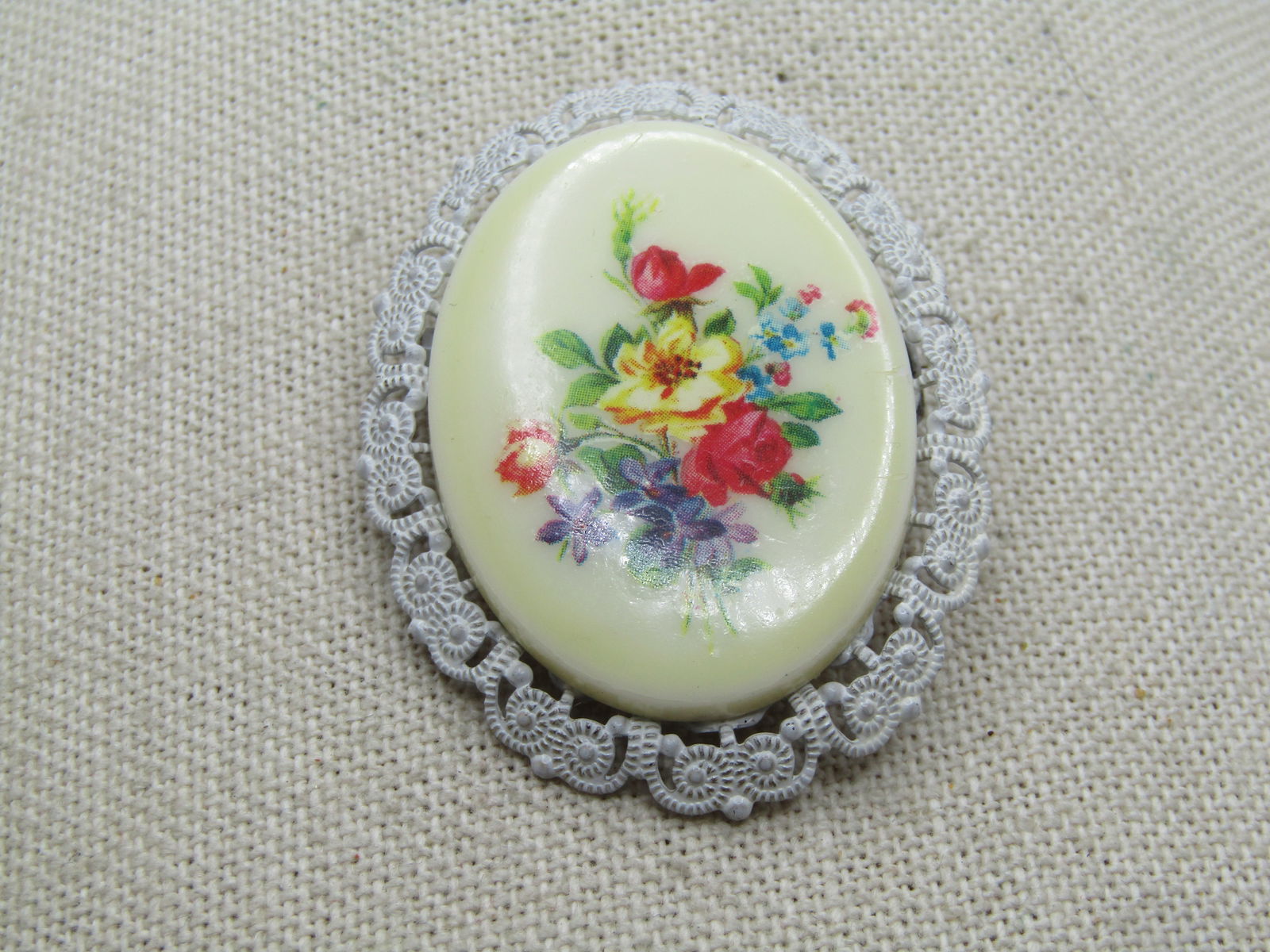 Vintage Floral Cameo Style Brooch, Germany, 1950's-1960's: Vintage Floral Cameo Style Brooch, Germany, 1950's-1960's. White enameled frame with a floral transfer design set on the oval off white plastic cameo-like center. It is appx. 2" tall and 1.5"