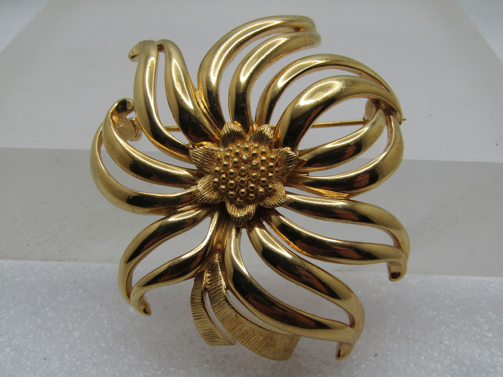 Vintage Gold Tone Blossom Brooch, Monet, 1960's-1970's: Vintage Gold Tone Blossom Brooch, Monet, 1960's-1970's. this is a gold tone blossom that is smooth on the petals with textured accents. Open space between the flowing petals that curve and curl