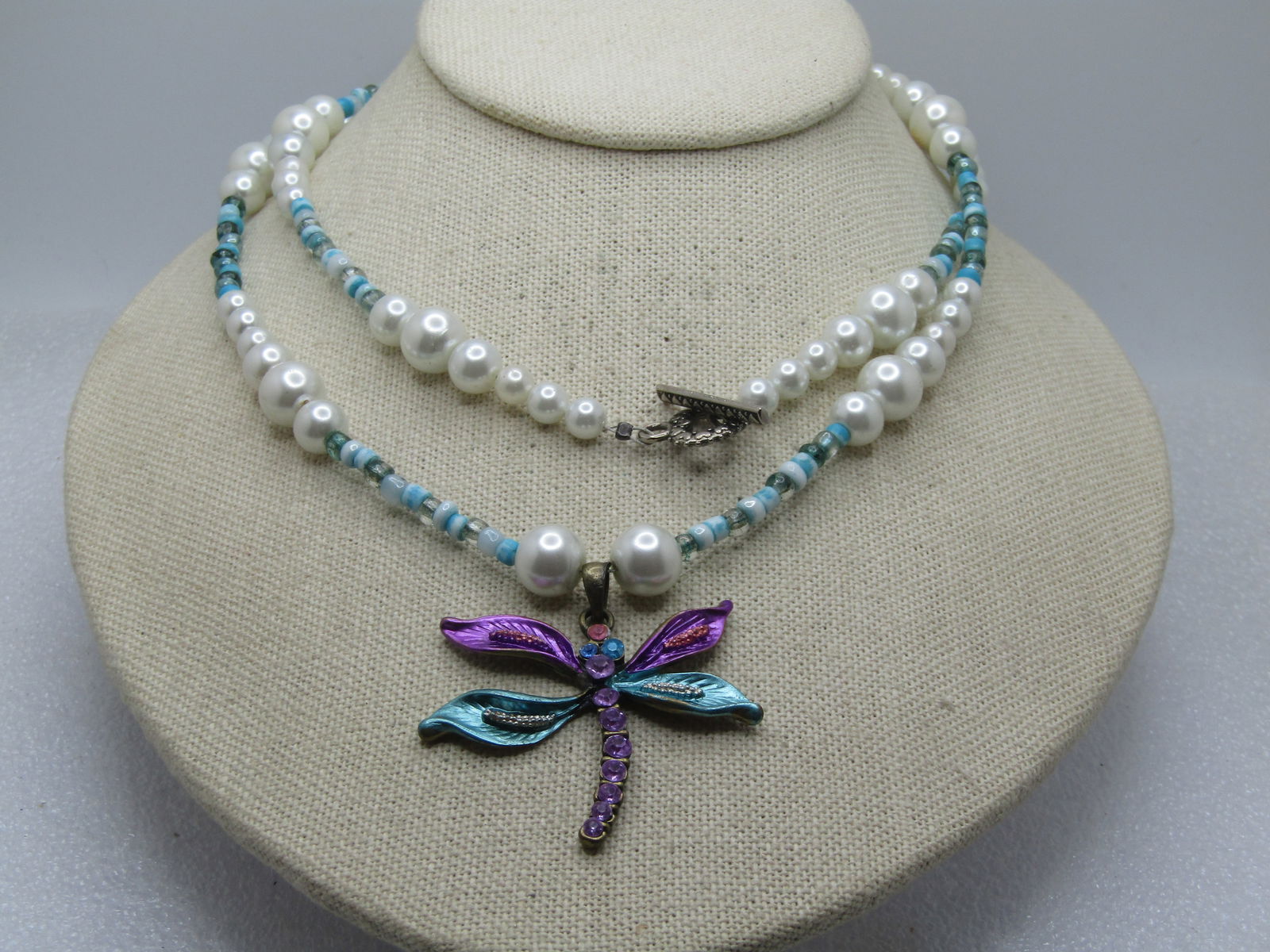 Vintage Rhinestone Dragonfly Faux Pearl Necklace, Aqua Glass Beads, 32" Toggle, 1980's-1990's: Vintage Rhinestone Dragonfly Faux Pearl Necklace, Aqua Glass Beads, 32" Toggle, 1980's-1990's. The dragonfly has aqua, pink rhinestones with metallic enameled aqua and ppink wings. The necklace is