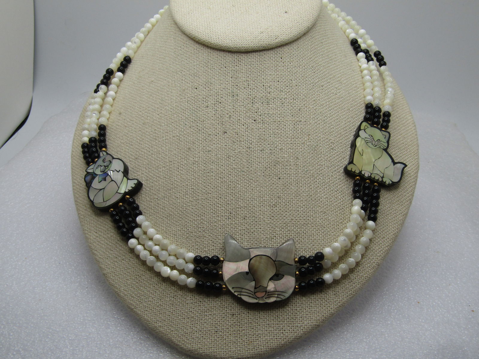 Vintage Inlaid Cat/Kitten Necklace, Triple Strand 19.5", With Box, 1970's-1990's: Vintage Inlaid Cat/Kitten Necklace, Triple Strand 19.5", With BoxTriple mother-of-pearl and black 4mm beaded necklace with gold tone beads and ornateend caps with lobster clasp. There are three
