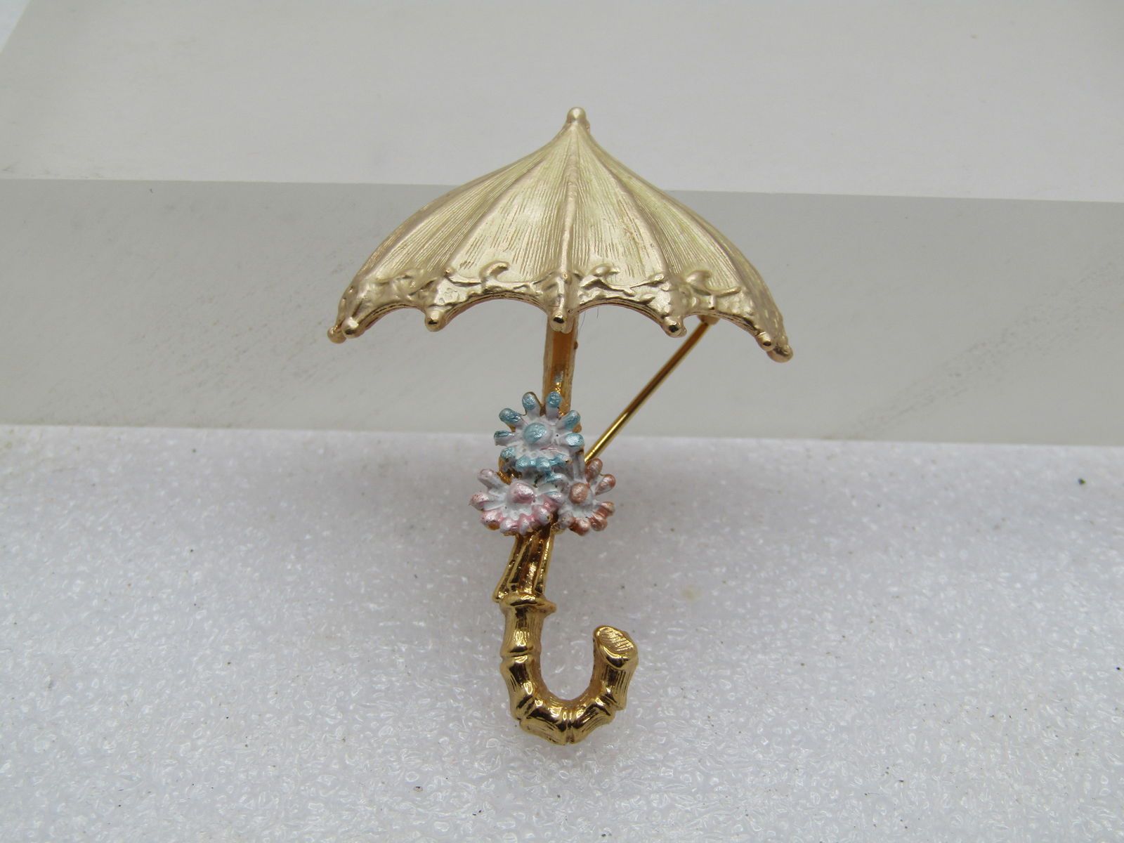 Vintage Umbrella & Enameled Floral Brooch, 1960's-1970's, Signed: Vintage Umbrella & Enameled Floral Brooch, 1960's-1970's, Signed . Gold tone satiny finish umbrella top and three pastel enameled flowers on the umbrella stem with textured curved handle. Very good