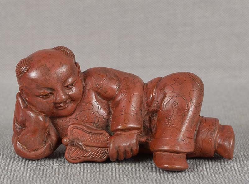 19c lacquer netsuke CHINESE BOY with fan: 19th century cinnabar lacquer netsuke of a reclining karako (Chinese boy) leaning on one hand and holding a fan in the other. Beautifully made, wonderful face, excellent depiction of hair tufts on