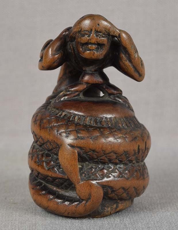 18c netsuke KIYOHIME turning into DRAGON: Late 18th to early 19th century boxwood netsuke of Kiyohime turning into a dragon and wrapped around the bell of Dojoji. Kiyohime was a daughter of an innkeeper whose advances on a monk were not