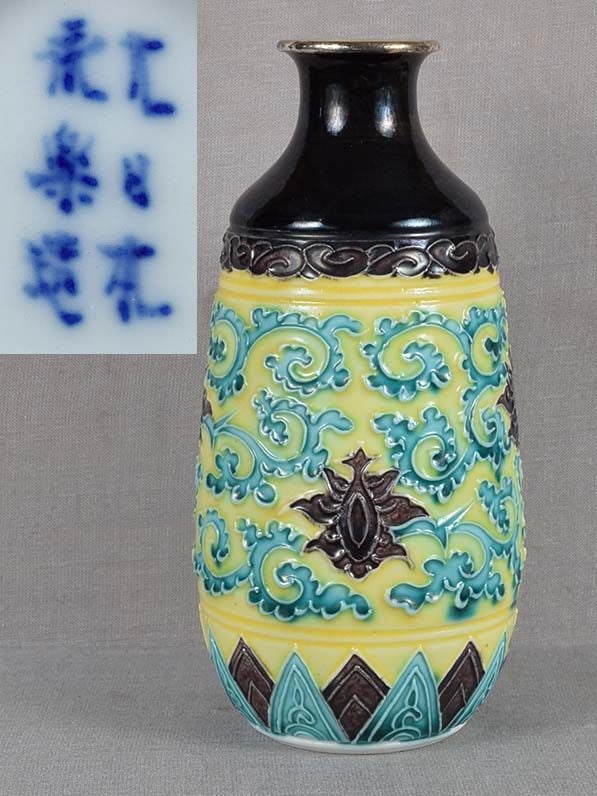 1900s Japanese porcelain tokkuri SAKE BOTTLE by EIRAKU: Unusual late Meiji (1900s) Japanese ceramic tokkuri - sake bottle - in classic shape with silver lining to the mouth and decoration of flowering lotus flowers among scrolling vines above stylized