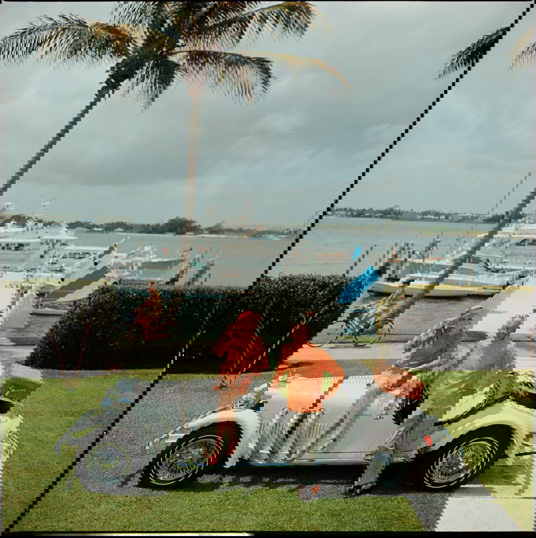 Slim Aarons Official Estate Print - All Mine - Oversize: 1968 (Printed later): Title: Slim Aarons Official Estate Print - All Mine - Oversize: 1968 (Printed later) Description: All Mine Jim Kimberly and his wife, with his white sports car and white boats moored on Lake Worth. A