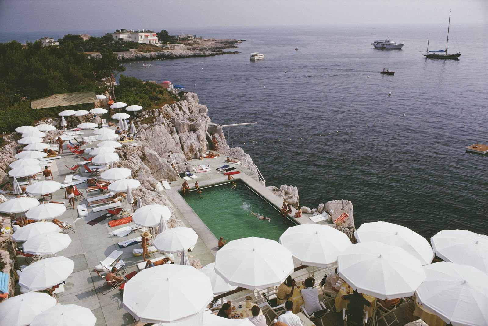 Slim Aarons 'Pool By The Sea' 1969 Official Limited Estate Edition: 1969 (printed later): Title: Slim Aarons 'Pool By The Sea' 1969 Official Limited Estate Edition: 1969 (printed later) Description: Pool By The Sea' Guests round the swimming pool at the Hotel du Cap Eden-Roc, Antibes,