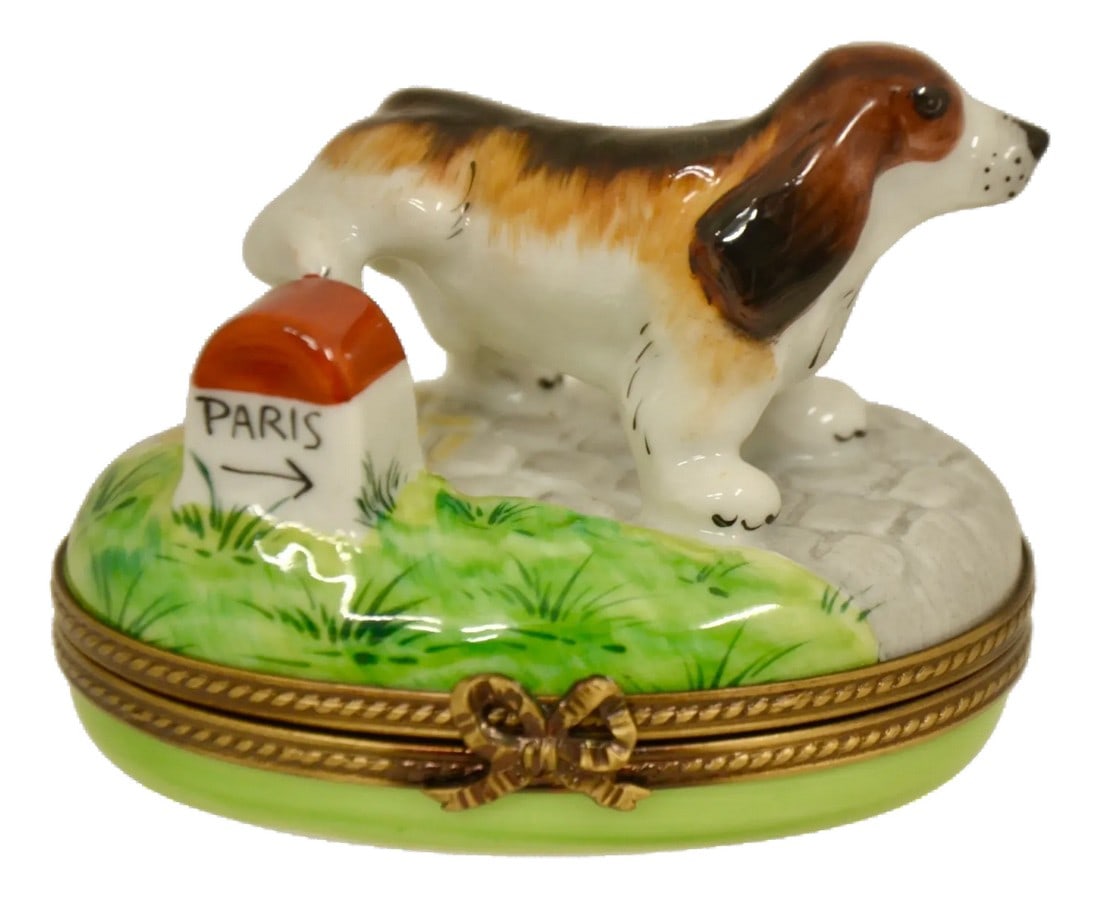 Limoges Dog Escapes to Paris Accent Box: Vintage hand painted Limoges of France trinket accent box designed as a long ear dog escaping to Paris in white, tan, brown, black has accents of green and red with a metal bow closure as well as a