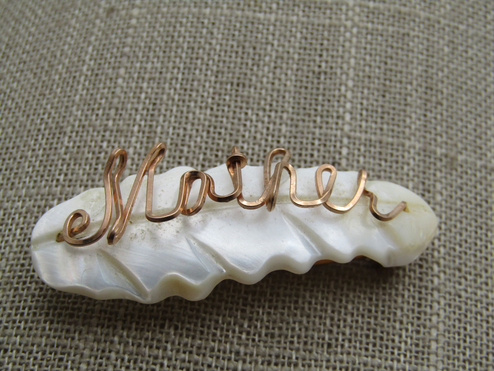 Vintage Carved MOP Mother Brooch, 1940's-1960's: Vintage Carved MOP Mother Brooch, 1940's-1960's. Carved leaf-like base with the word MOTHER in cursive made with square 10kt G.F. wire over the mother-of-pearl. C-Clasp. It is appx. 2" wide and