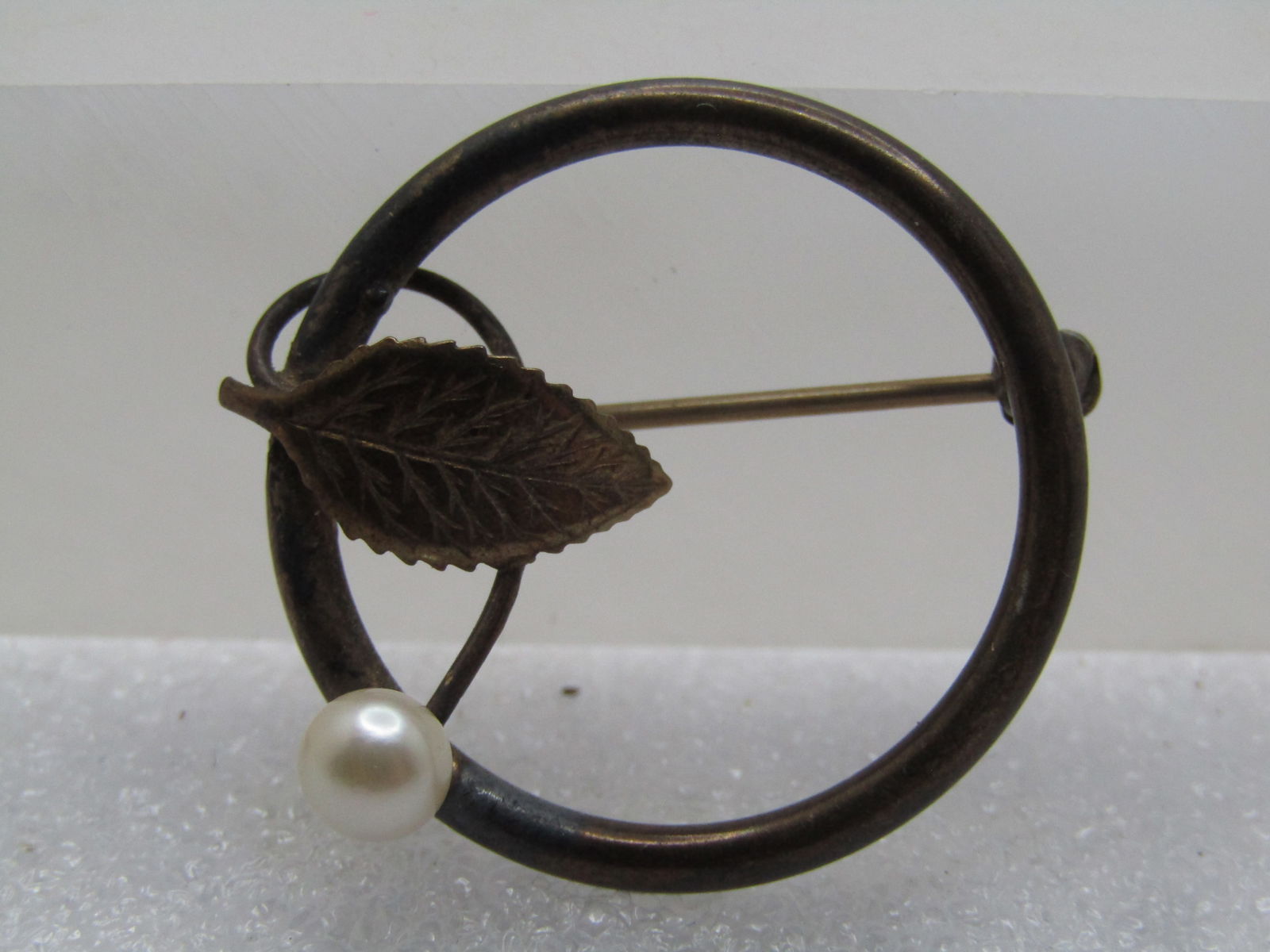 Vintage 14kt GF Faux Pearl Leaf Brooch, Circle, Signed DCE, 1960's: Vintage 14kt GF Faux Pearl Leaf Brooch, Circle, Signed DCE, 1960's. It is appx. 1-1/8" across with an appx. 4.5mm white faux pearl on a stem that extends slightly beyond the frame and a singled leaf