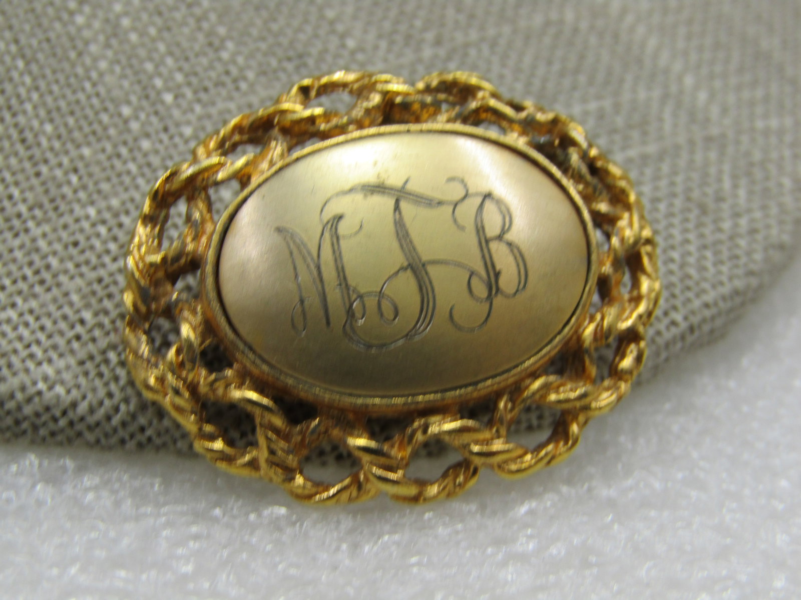 Vintage Initials MJB Brooch, Woven Frame, 1.25" 1960's-1970's: Vintage Initials MJB Brooch, Woven Frame, 1.25" wide and 1-1/8" tall, 1960's-1970's gold tone. It has a satiny domed gold tone center with a bezel frame around that engraved val with a rope accent