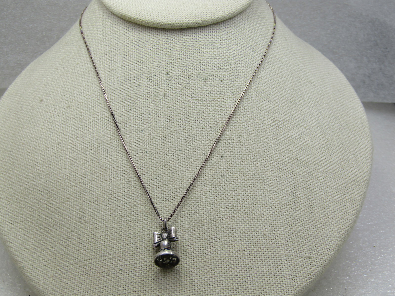 Vintage Sterling Bell Necklace, 16", 1960's-1970's: Vintage Sterling Bell Necklace, 16", 1960's-1970's. The bell is appx. 3/4" long and 3/8" wide with a bow on top and an openwork scroll near the bottom edge. It is on a 1mm box chain that is marked