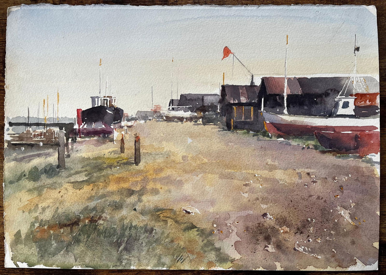 Anthony Herbert; Coastal Boatyard with Fishing Huts Beached Boats and Red Flag Watercolour Scene - 5