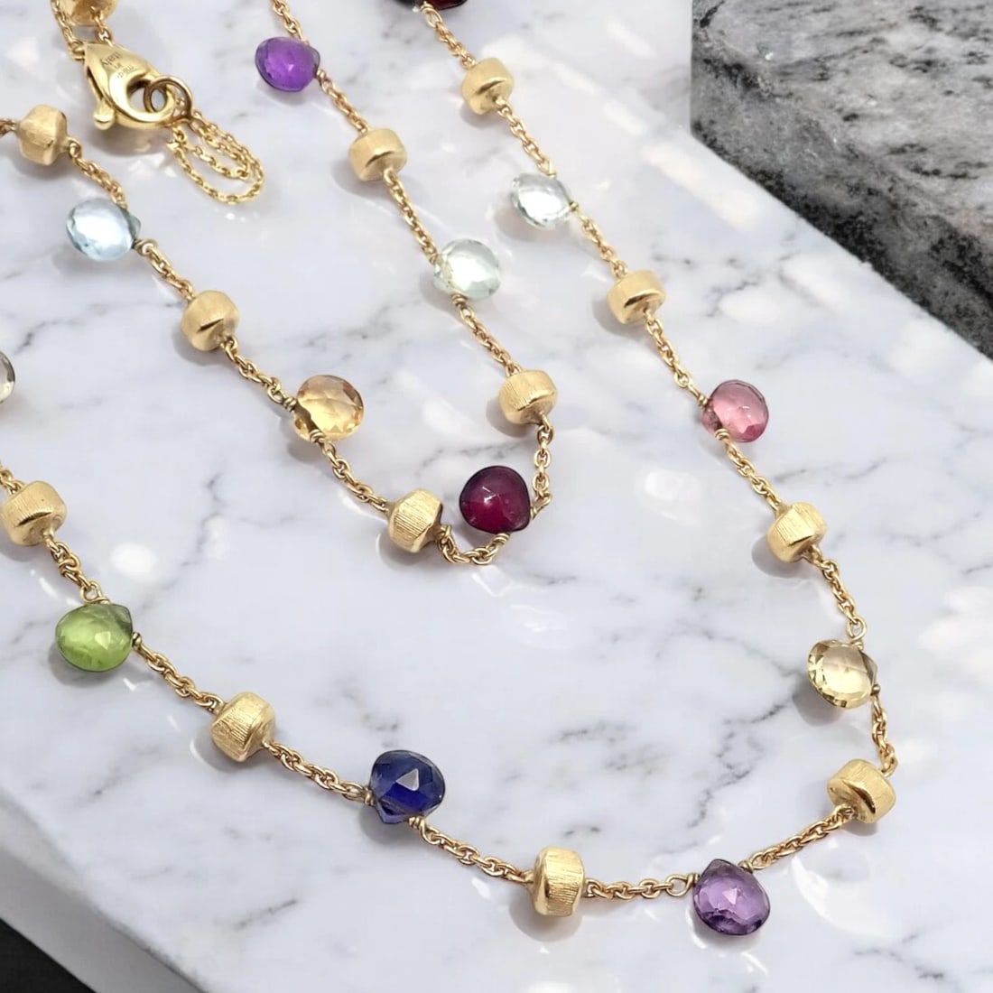 Authentic! Marco Bicego 18k Yellow Gold Multicolor Stones Paradise Necklace: The Marco Bicego 18k Yellow Gold Paradise Necklace showcases an array of vibrant, multicolored gemstones, elegantly set along a delicate gold chain. Each stone is uniquely shaped, adding a playful yet