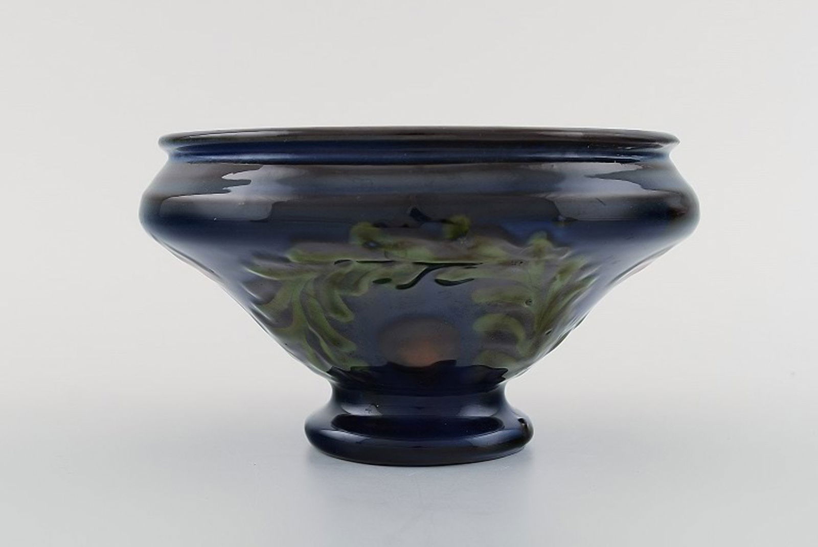 Kähler, Denmark. Bowl in glazed ceramics. Green leaves and red berries on a dark blue: Title: Kähler, Denmark. Bowl in glazed ceramics. Green leaves and red berries on a dark blue background. 1930 / 40s. Description: Kähler, Denmark. Bowl in glazed ceramics. Green leaves and r